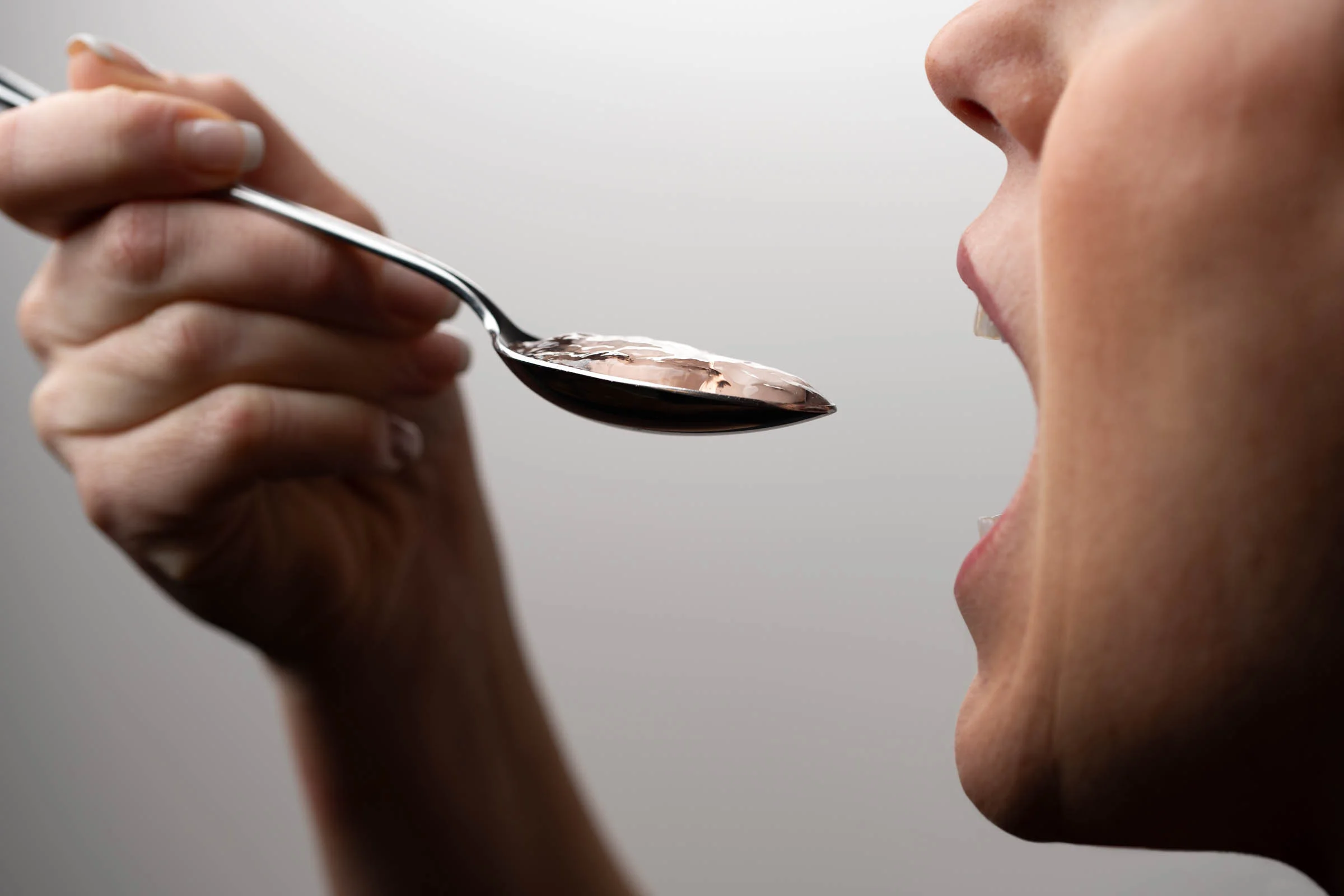 Person using a spoon to take medication with Gloup®